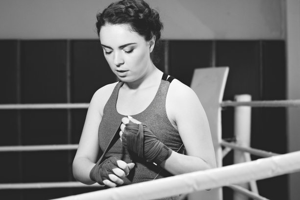 美丽的拳击女孩的肖像包裹拳击包裹在环。在体育馆训练。喜欢运动的女性在做拳击练习。黑白照片。图片下载
