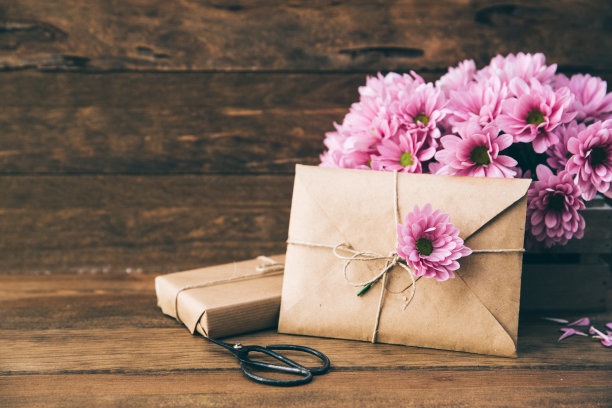 在木质背景上制作信封和鲜花。空间的文本图片下载