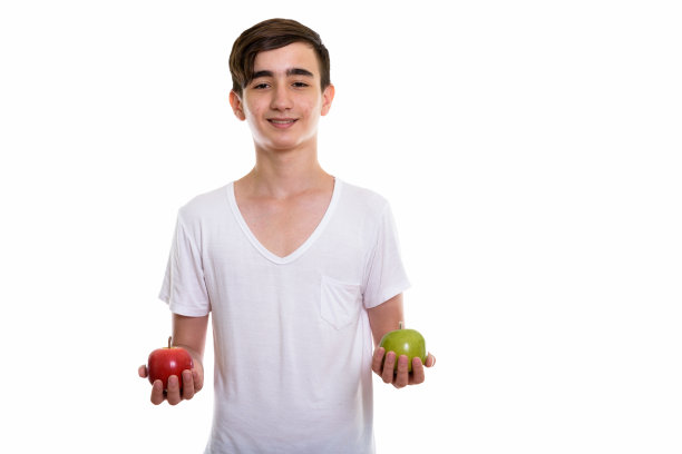 快乐的波斯青少年手拿红苹果和绿苹果的影棚照片图片下载