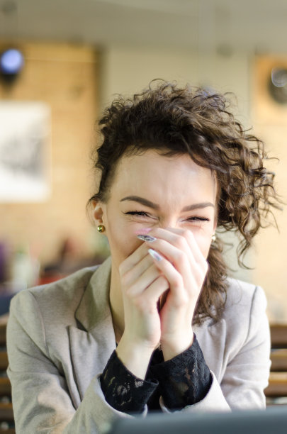 一头卷发的女孩坐在咖啡馆的桌子旁图片下载