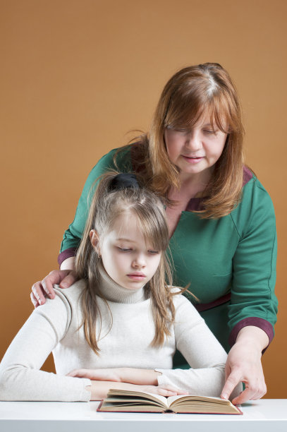 一个女人和一个十岁的女孩在看书。图片下载