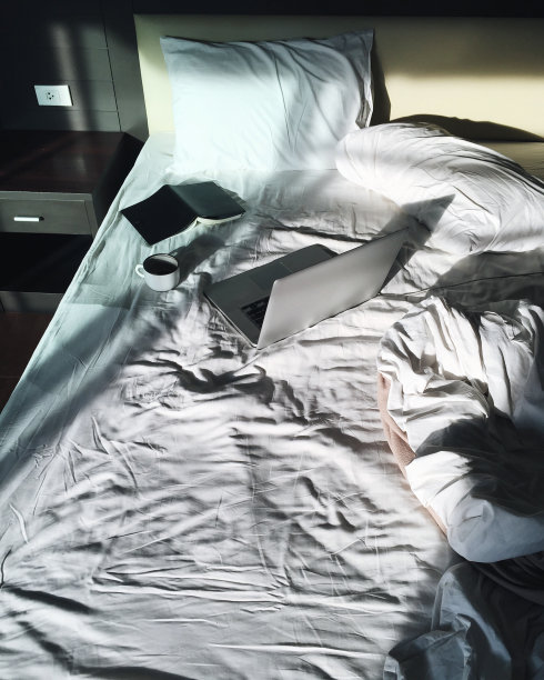 休闲自由职业者在早上工作的床上喝着咖啡和笔记本图片下载