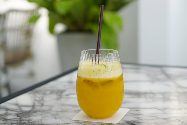一杯新鲜的百香果汁和半百香果放在大理石桌上-自制的有机冷榨果汁。图片下载