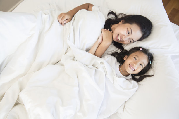 快乐的亚洲母亲和女儿放松和睡在卧室的白色床上图片下载