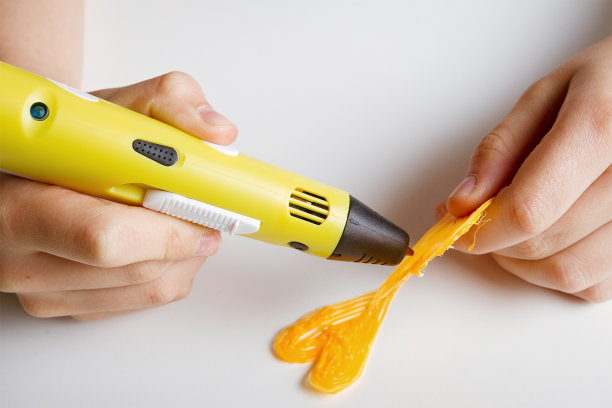 孩子们手拿着黄色的3D打印笔，上面有细丝，做成心形。图片下载