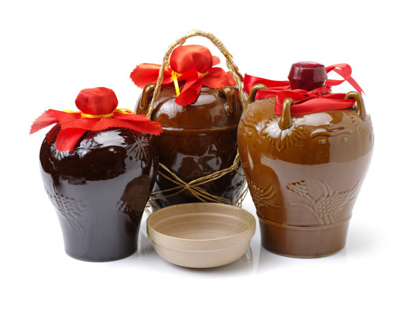 米酒在陶瓷罐中孤立在白色的背景上素材图片