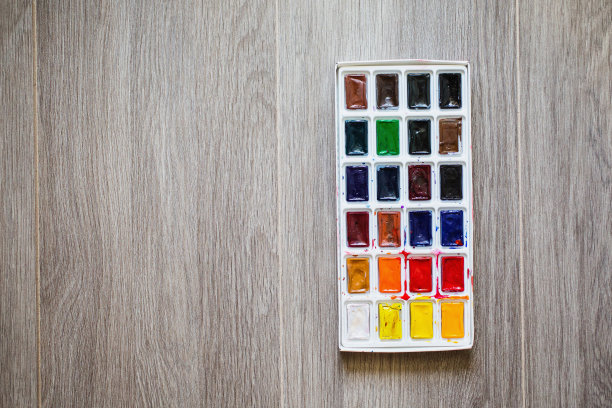 木质背景上的高水彩颜料。绘画工具，学生，艺术家和爱好者。24种颜色的调色板水彩关闭。使用油漆。一套暖色和冷色。的纹理。固体水彩瓷砖。明亮的h图片下载