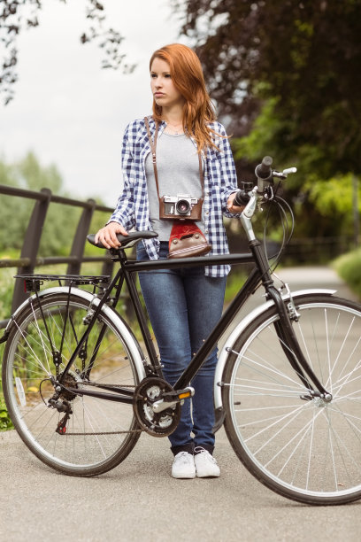 漂亮的红头发和自行车站在一起图片下载