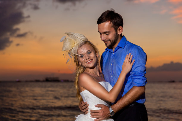 新郎和新娘在热带海滩上，夕阳为背景图片下载