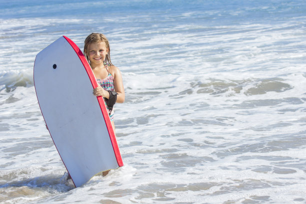 可爱的女孩在海里玩冲浪板图片下载