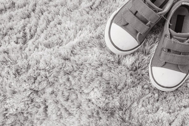 特写面料运动鞋的孩子在灰色地毯纹理背景在顶视图在黑白色调与复制空间图片下载