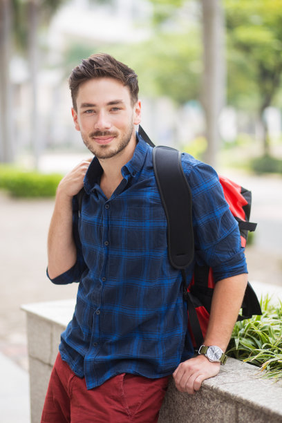 正面英俊的旅行者坐在花坛上图片下载