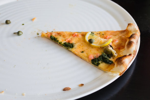 白色盘子里的最后一片披萨。黑色背景的意大利国菜，芝士，香料和贻贝。大餐。暴食图片下载