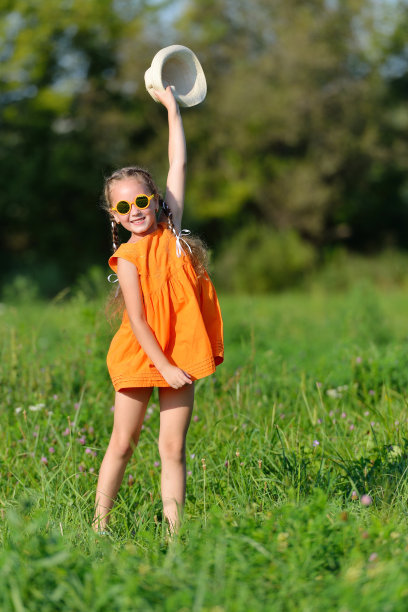 快乐的年轻女孩，太阳眼镜跳在草地上玩图片下载
