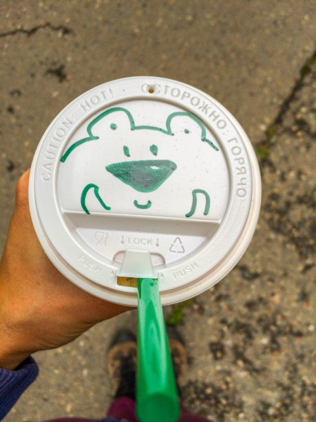 年轻女性手持带有熊脸图案的咖啡杯图片下载