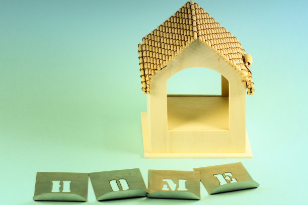 在浅蓝色背景上用金属模板制作的带有“家”字样的木屋模型。图片下载