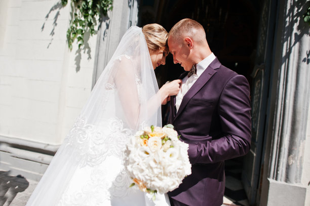 婚礼当天，新娘为新郎系领扣。素材图片