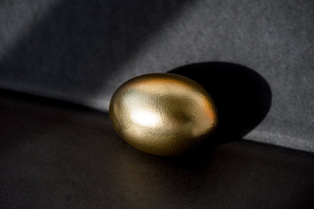 金蛋是财富和投资的象征，放在金箔上。出色的照片。暗的背景图片下载