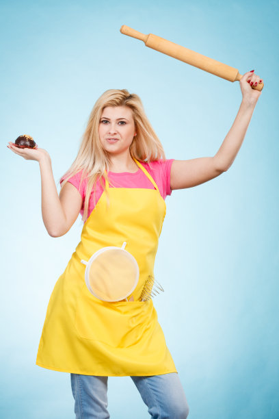 拿着纸杯蛋糕，擀面杖，穿着围裙的漏勺的女人图片下载