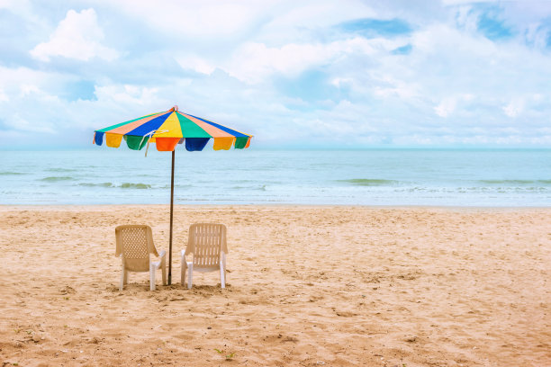 海滩上的两把椅子和沙滩伞，中午的时候天空和云很好。节日的概念,放松图片下载