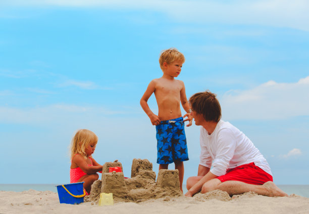 父亲和儿子和女儿在海滩上建造城堡图片下载