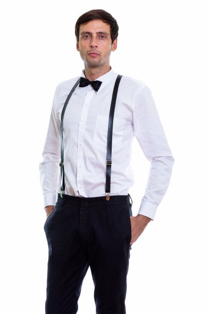 工作室拍摄的年轻英俊的男子站着，而穿着背带和领结图片下载