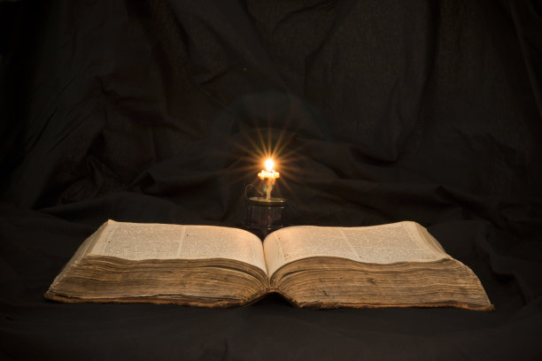 打开书，用灯光照亮文本。开卷阅读教育读者。在黑色背景上阅读古代圣经文本。俄罗斯《圣经》图片下载