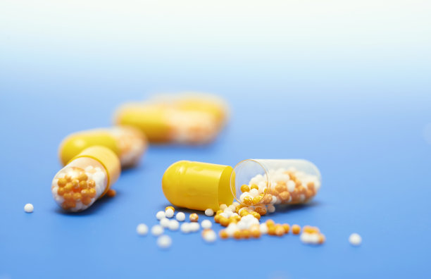 分开开的黄色胶囊在蓝色梯度背景图片下载
