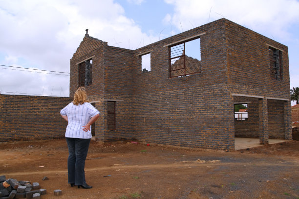 年轻女子看着未完工的房子。图片下载