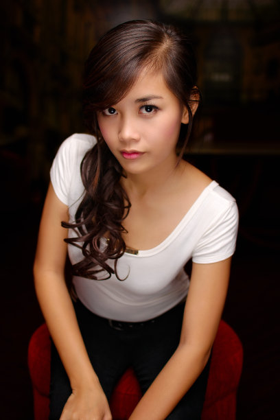 迷人的年轻亚洲女人向前倾，直视前方图片下载