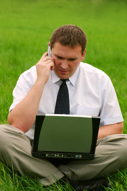 带着笔记本电脑坐在草地上的商人图片下载