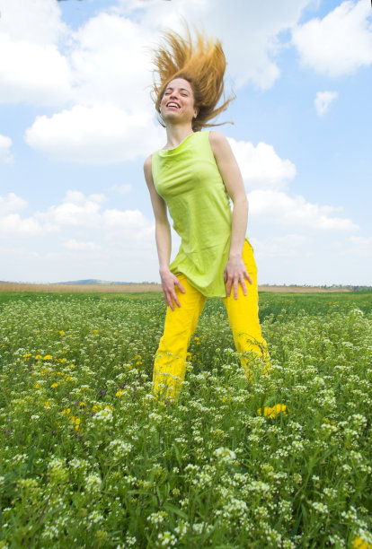 年轻女子站在绿色的田野上，春意盎然图片下载