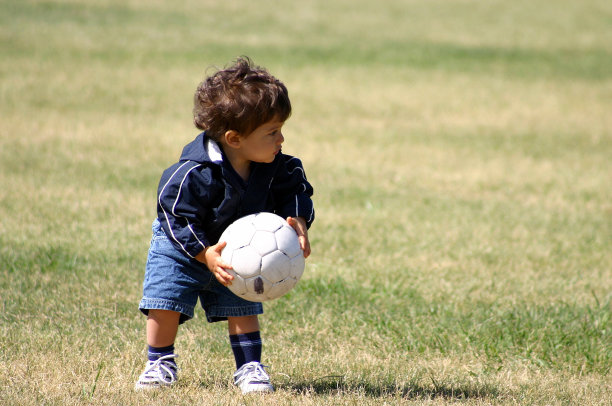 蹒跚学步的小男孩拿着足球图片下载