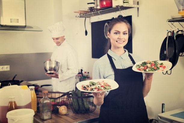 年轻的女服务员穿着围裙微笑的肖像图片下载