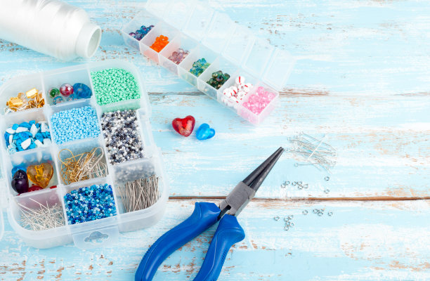 手工背景与copyspace。盒子与珠子，线轴，钳子和玻璃心创建手工珠宝在旧的木制背景。手工配件和工具图片下载