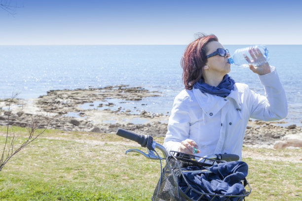 中年妇女骑自行车休息时喝水图片下载