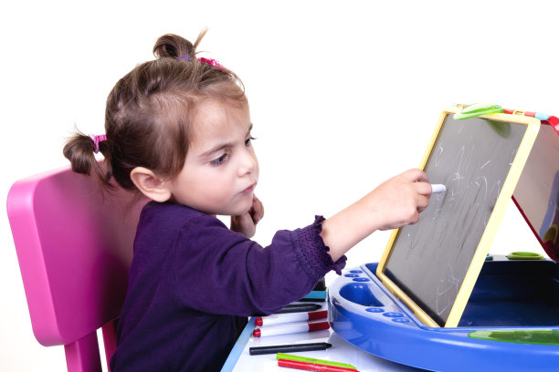 小女孩正在用粉笔在黑板上写字图片下载