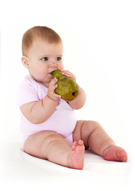 快乐的小女孩吃了一个梨。图片下载