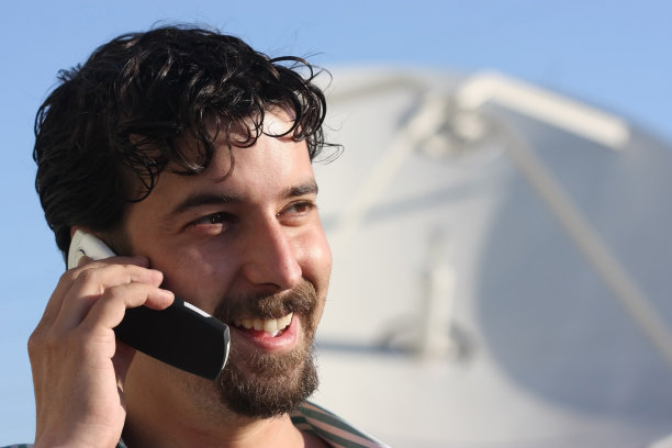 男人在用手机，背景是卫星天线图片下载