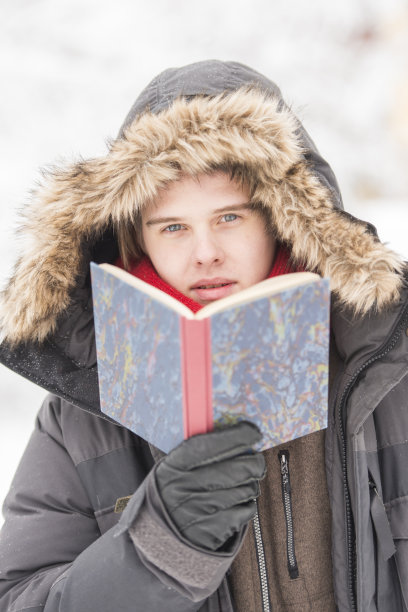 迷人的年轻人在冬天的衣服读一本书图片下载