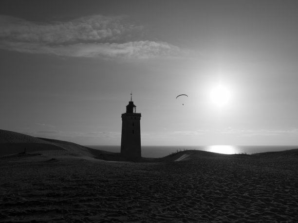 日落时灯塔附近的滑翔伞图片下载