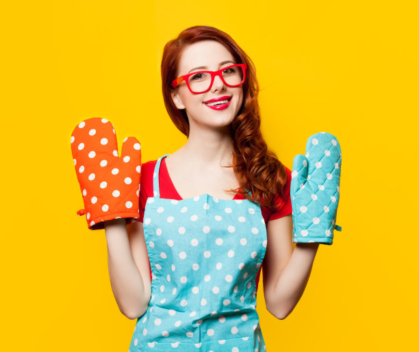 年轻女子穿着围裙，戴着烤箱手套图片下载