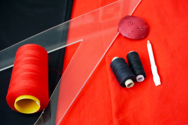 缝纫过程:红黑线，一套针，一把尺子和一支铅笔在织物的背景上图片下载