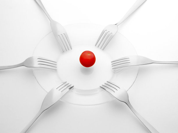 红番茄和六把黑白叉子。分享、竞争、短缺、竞争的概念。图片下载