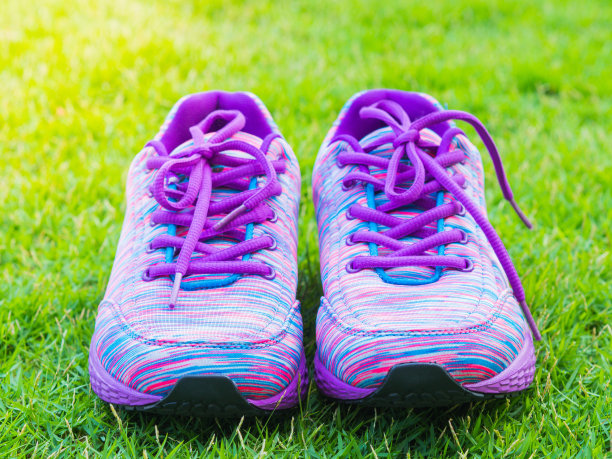 一双粉红色的运动鞋和一个水瓶在绿色的草地上。在森林或公园小径的背景。跑步运动配件。图片下载