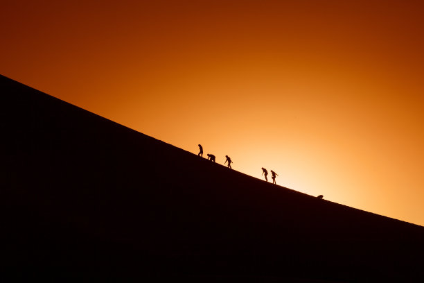 试图爬山的队伍的剪影。体育运动图片下载