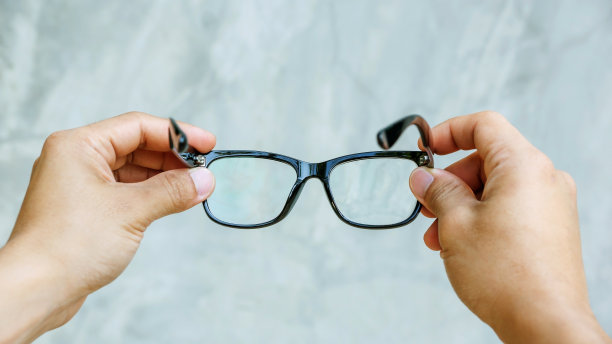 在灰色背景下拿着眼镜的男人。图片下载