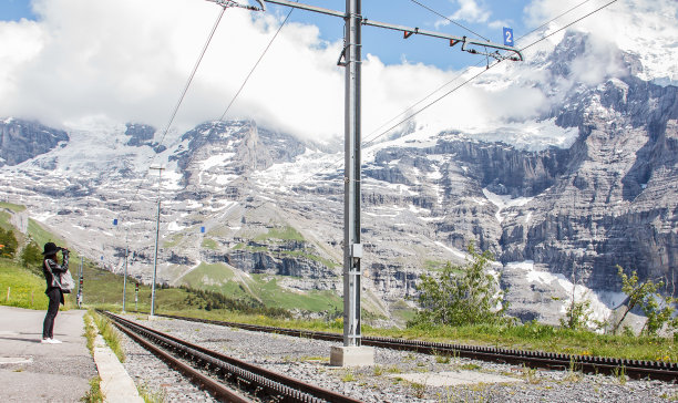 亚洲妇女等待瑞士铁路列车从克莱因Scheidegg站与美丽宏伟的瑞士阿尔卑斯山脉，翁格纳尔普，伯尔尼，瑞士，欧洲。从Kleine Scheidegg到Lauterbrunnen的铁路图片下载