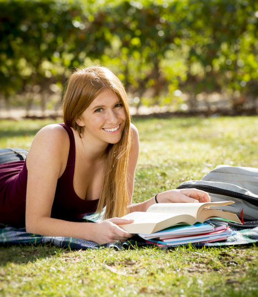 十几岁的学生女孩在校园公园草学习书快乐图片下载