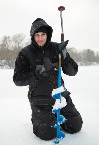 一个年轻人在冰上钻洞图片下载